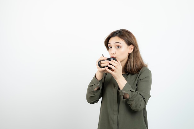 ホットコーヒーのカップを飲む愛らしい少女の写真。高品質の写真