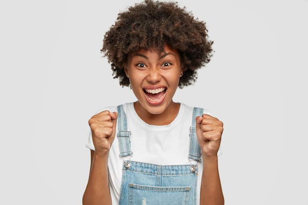 La foto della giovane donna nera infastidita e indignata stringe i pugni con rabbia, ha un'acconciatura afro