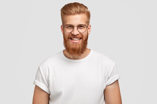 Photo of attractive ginger man with satisfied expression, has thick beard