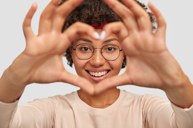 Free photo photo of attractive young woman makes heart shape gesture over face