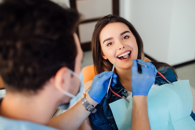 현대 클리닉에서 환자와 함께 일하는 전문 치과 의사의 뒷모습 사진.