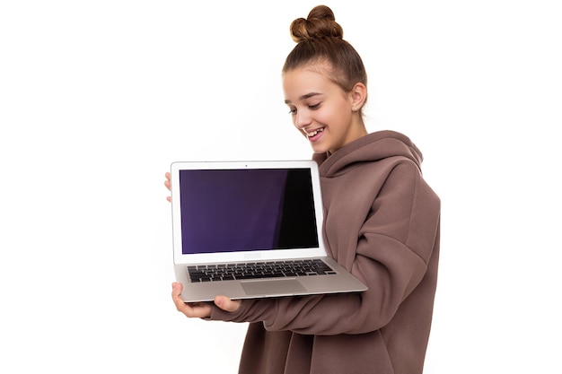 Photo of a beautiful positive cute girl with dark hair and a bun in a brown hoodie with a hood holds