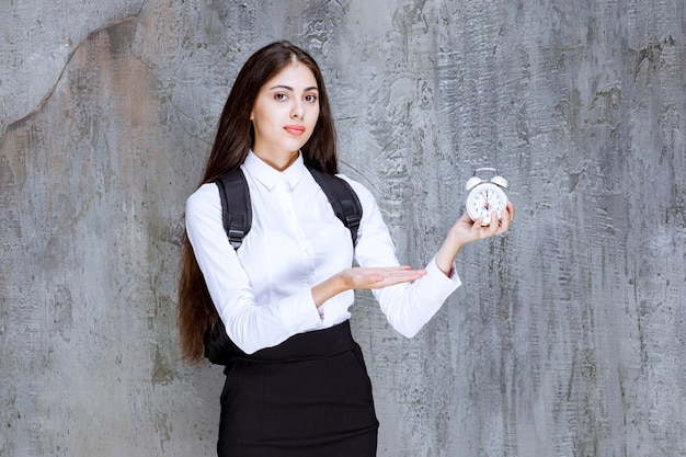 Photo of beautiful student in formal outfit showing time. High quality photo