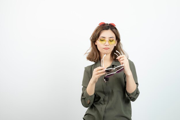 Photo of beautiful woman holding colorful sunglasses over white. High quality photo