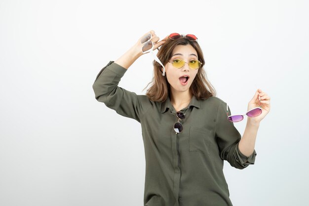 Photo of beautiful woman holding colorful sunglasses over white. High quality photo