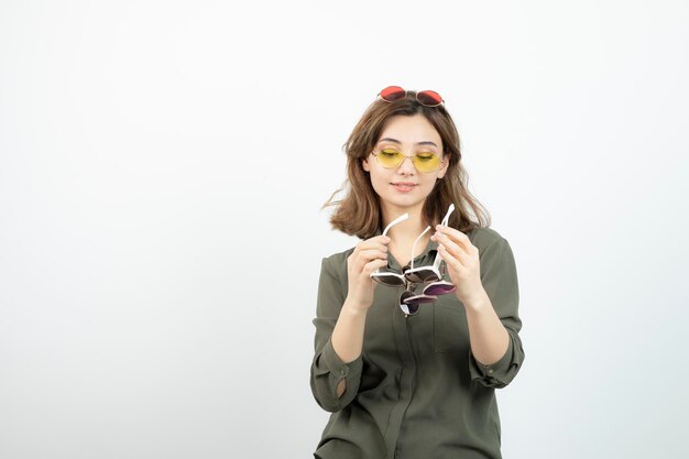 Photo of beautiful woman holding colorful sunglasses over white. High quality photo