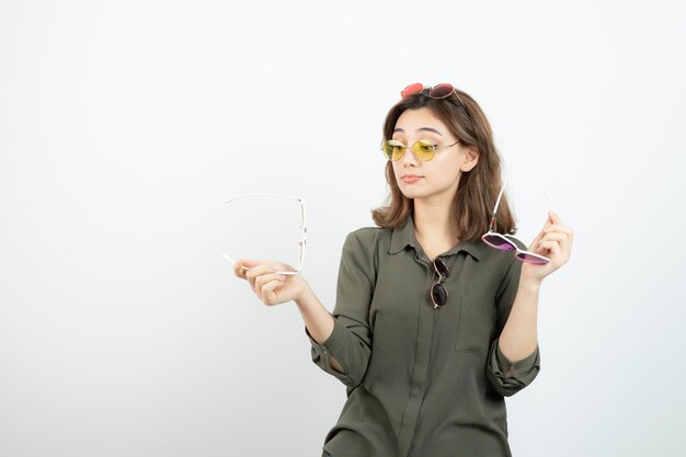 白の上にポーズをとってカラフルなサングラスをかけた美しい女性の写真。高品質の写真