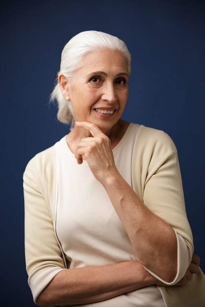 Photo of charming mature woman in beige tshirt, holding her chin