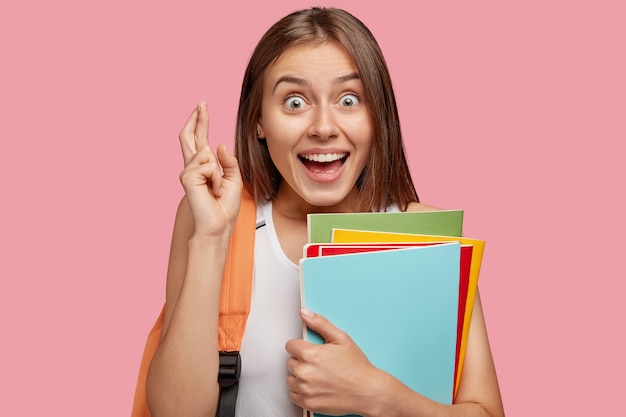 Free photo photo of cheerful brunette woman with overjoyed look keeps fingers crossed