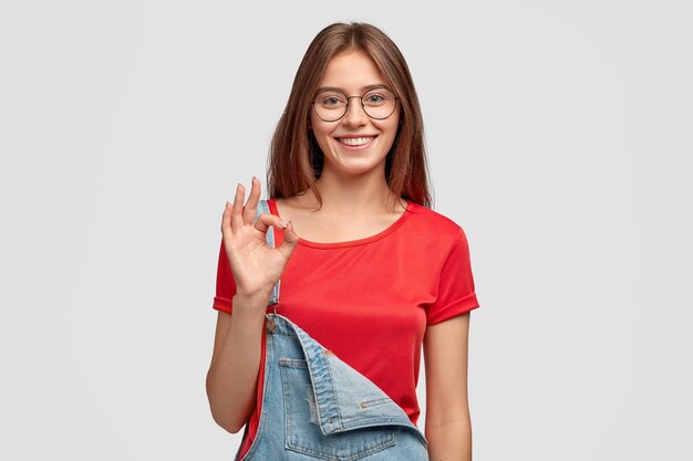 Photo of cheerful young woman shows zero or okay gesture, shows her approval