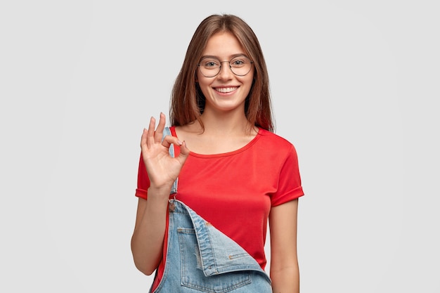 Фотография жизнерадостной молодой женщины показывает нулевой или нормальный жест, показывает ее одобрение