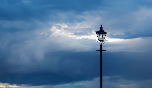 Photo of cloudy sky at dusk with classic streetlight