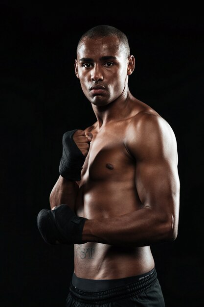Фотография сосредоточенного красивого молодого сильного афроамериканского боксера, позирующего