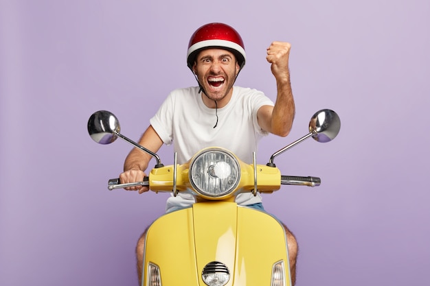 Photo of confident guy with helmet driving yellow scooter