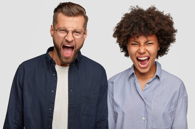 Photo of crazy angry young man and woman of different races exclaim with annoyance