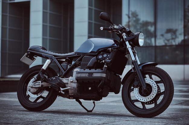 Photo of a custom-made retro motorcycle against a skyscraper.