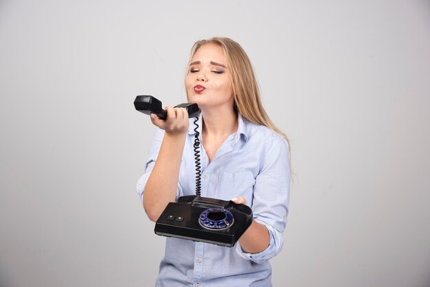 Photo of a cute woman model standing and holding black old handset