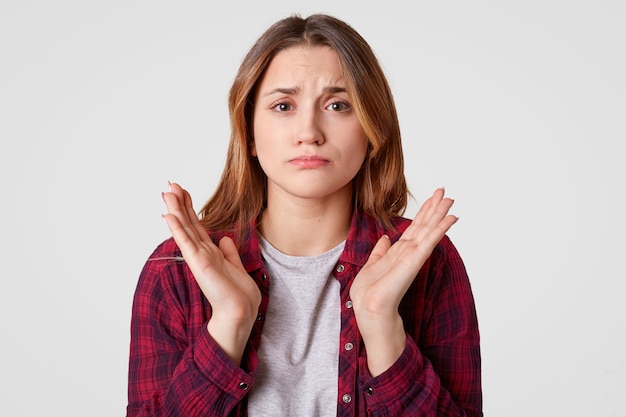Free photo photo of displeased european woman spreads palms, has pity facial expression, wears casual clothes, isolated over white wall, doubts about something. people, disappointment, dissatisfaction