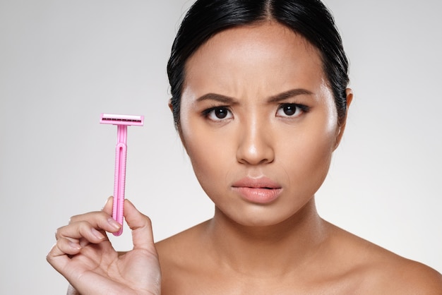 Photo of displeased woman showing razor