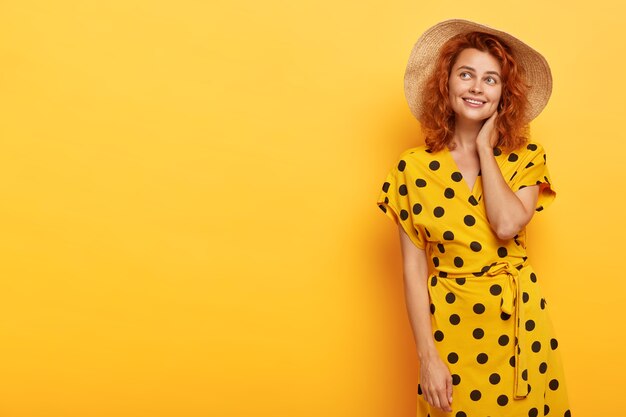 Photo of dreamy lovely redhead woman posing in yellow polka dress and straw hat