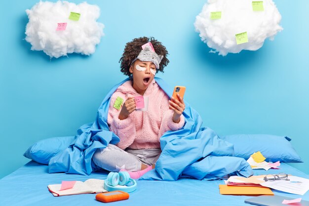 Photo of exhausted female student yawns has sleepy expression prepares for exam