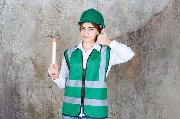 Photo of female construction worker in green helmet holding hammer