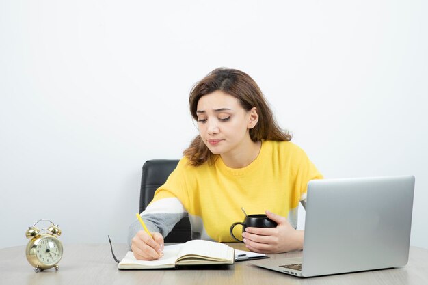 Photo of female office worker sitting at the desk and writing in clipboard . High quality photo