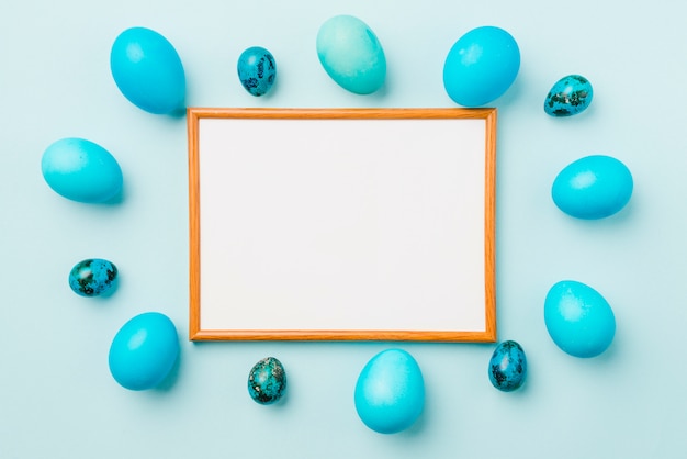 Free photo photo frame between blue set of easter eggs