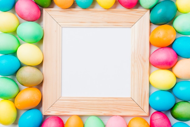 Free photo photo frame between bright collection of easter eggs