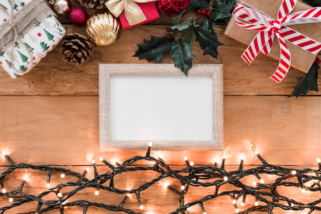 Photo frame between Christmas decorations and illuminated fairy lights