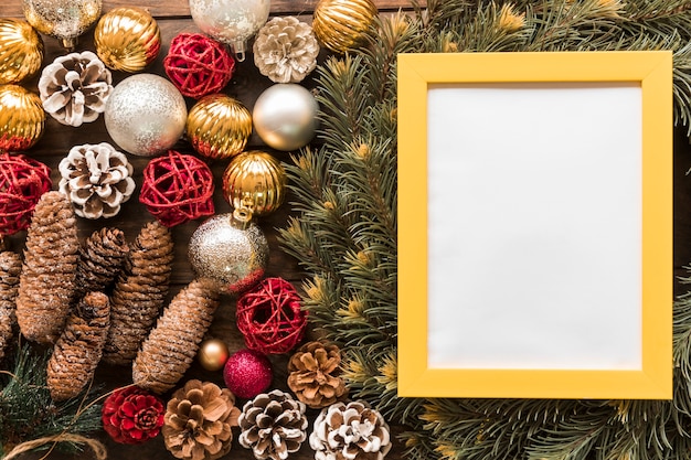 Photo frame between fir branches, ornament snags and Christmas balls