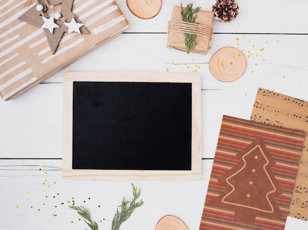 Photo frame between gift boxes in wraps and Christmas decorations