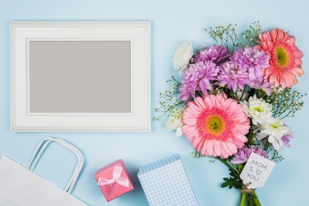 패킷, 선물 및 노트북 근처 태그에 제목과 신선한 꽃의 꽃다발 근처 사진 프레임