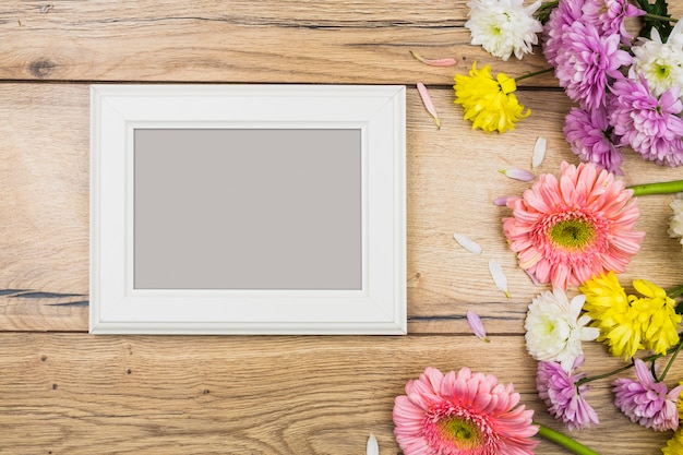 Photo frame near fresh bright flowers on desk