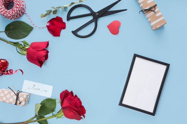 Photo frame near scissors, flowers and bobbin of twists