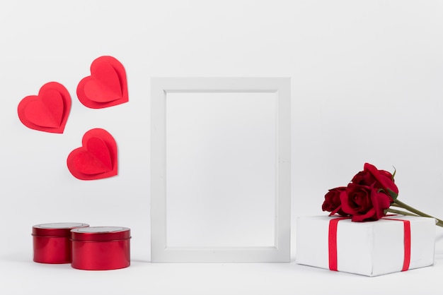 Фоторамка между подарками с цветами, бумажными сердечками и коробками