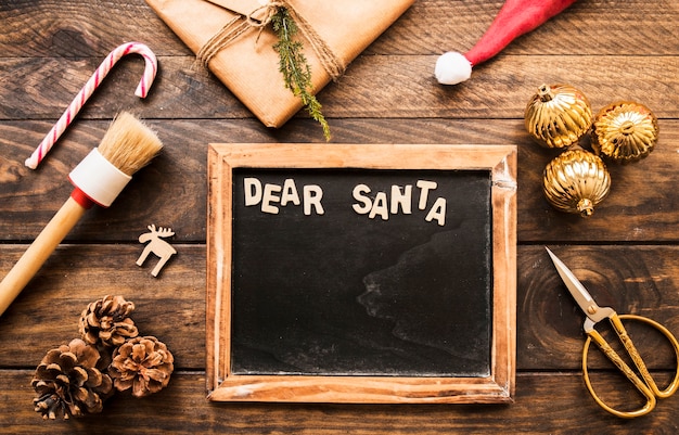 Photo frame with dear Santa inscription near present box, snags and ornament balls