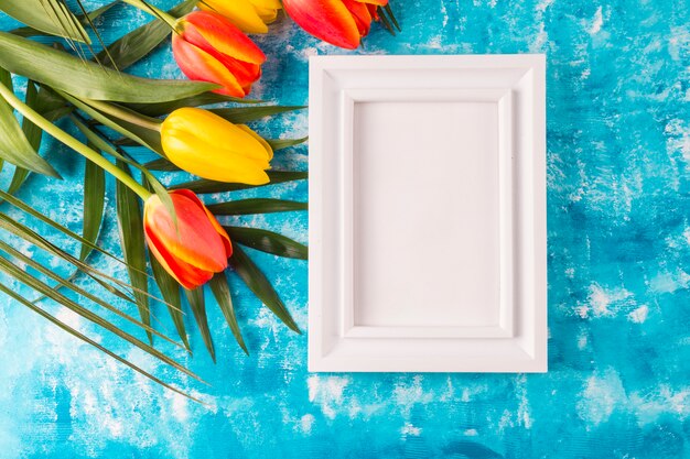 Photo frame with flower bouquet on blue background