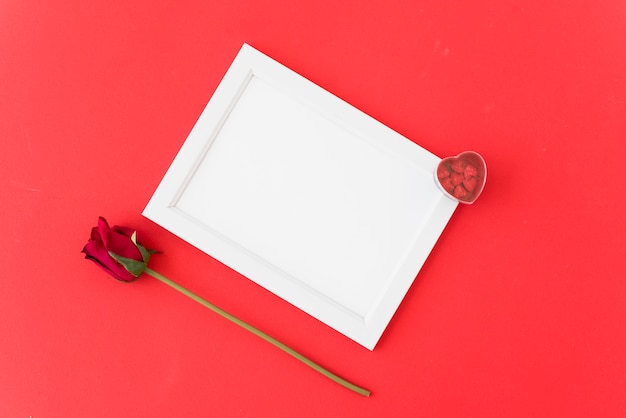 Photo frame with ornament hearts near flower