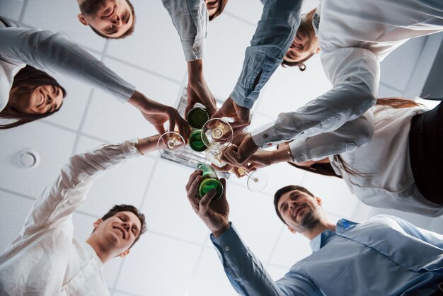 Photo from below. Knocking glasses in the office. Celebrating success