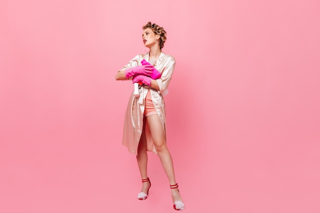 Photo In full growth of woman in bathrobe holding detergent on pink wall