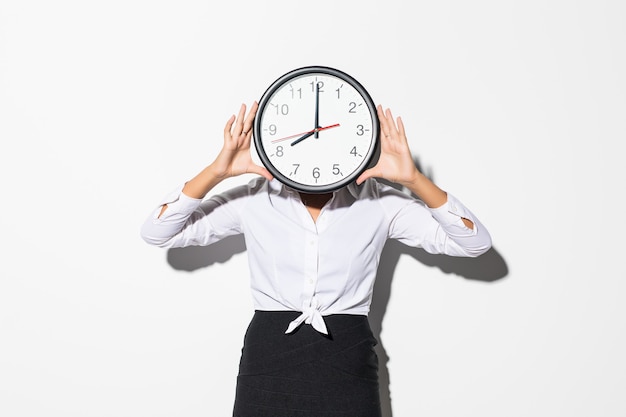 Photo of funny woman in on white shirt and black skirt coning face with big round clock isolated on white