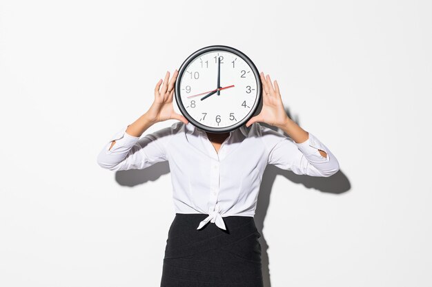 Photo of funny woman in on white shirt and black skirt coning face with big round clock isolated on white