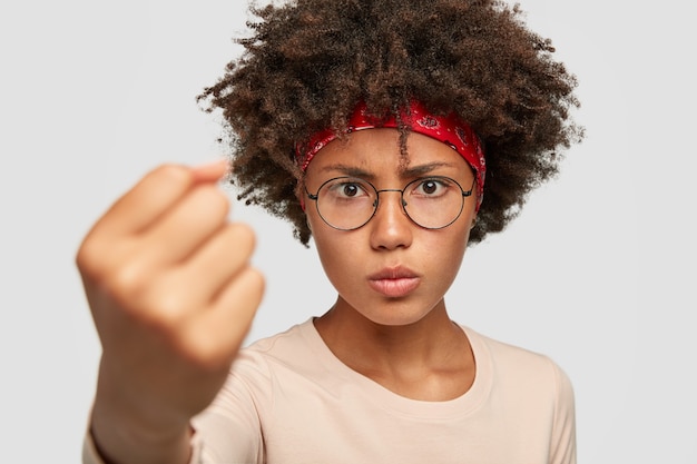 분노한 여자의 사진은 주먹을 보여주고, 그녀의 힘을 보여주고, 위협으로 화가 나서 보입니다.