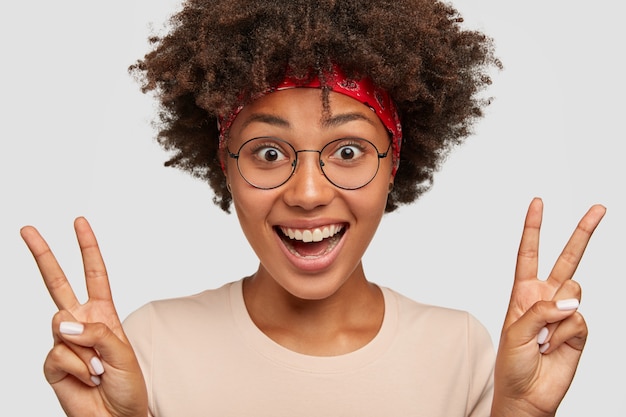 Photo of glad Afro American lady shows victory or peace sign