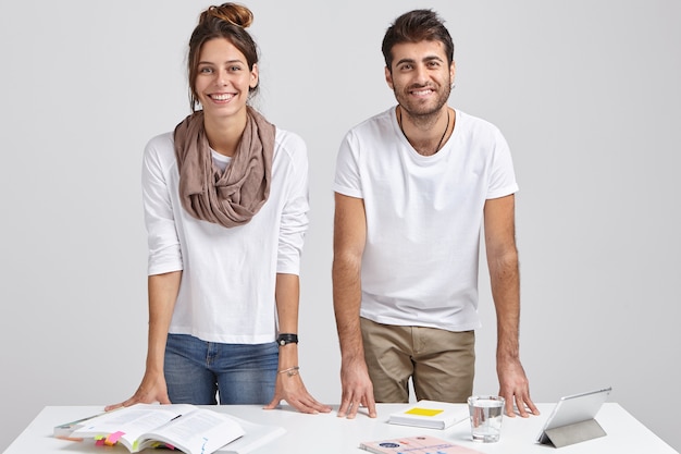 Free photo photo of glad young female and male students lean at table