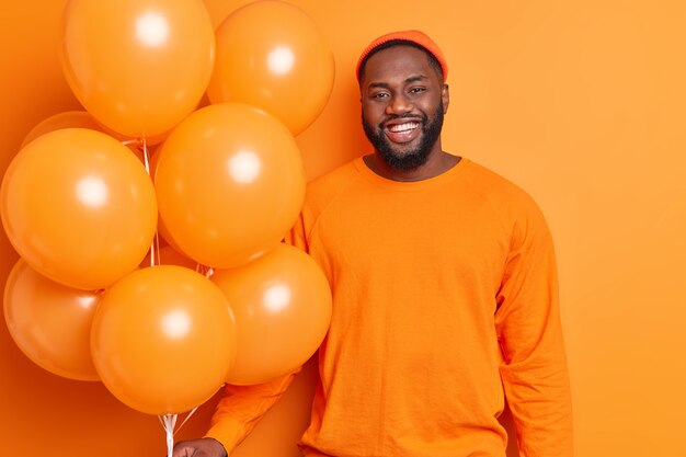 Photo of handsome bearded dark skinned man smiles joyfully