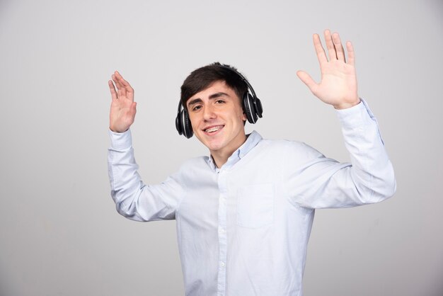 Photo of a handsome guy model dancing in headphones and looking at camera