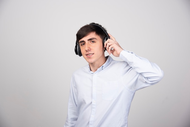 Photo of a handsome guy model standing in headphones and looking at camera