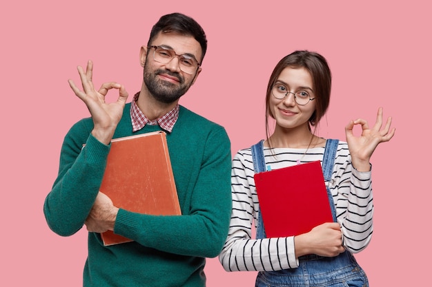 Free photo photo of handsome male student and his female groupmate demonstrates okay gesture, agree with something